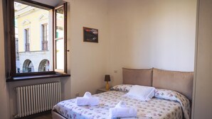 Habitación de hotel con cama, ventana, radiador y una mesita con lámpara.