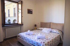 Une chambre d’hôtel avec un lit, une fenêtre, un radiateur et une petite table avec une lampe.
