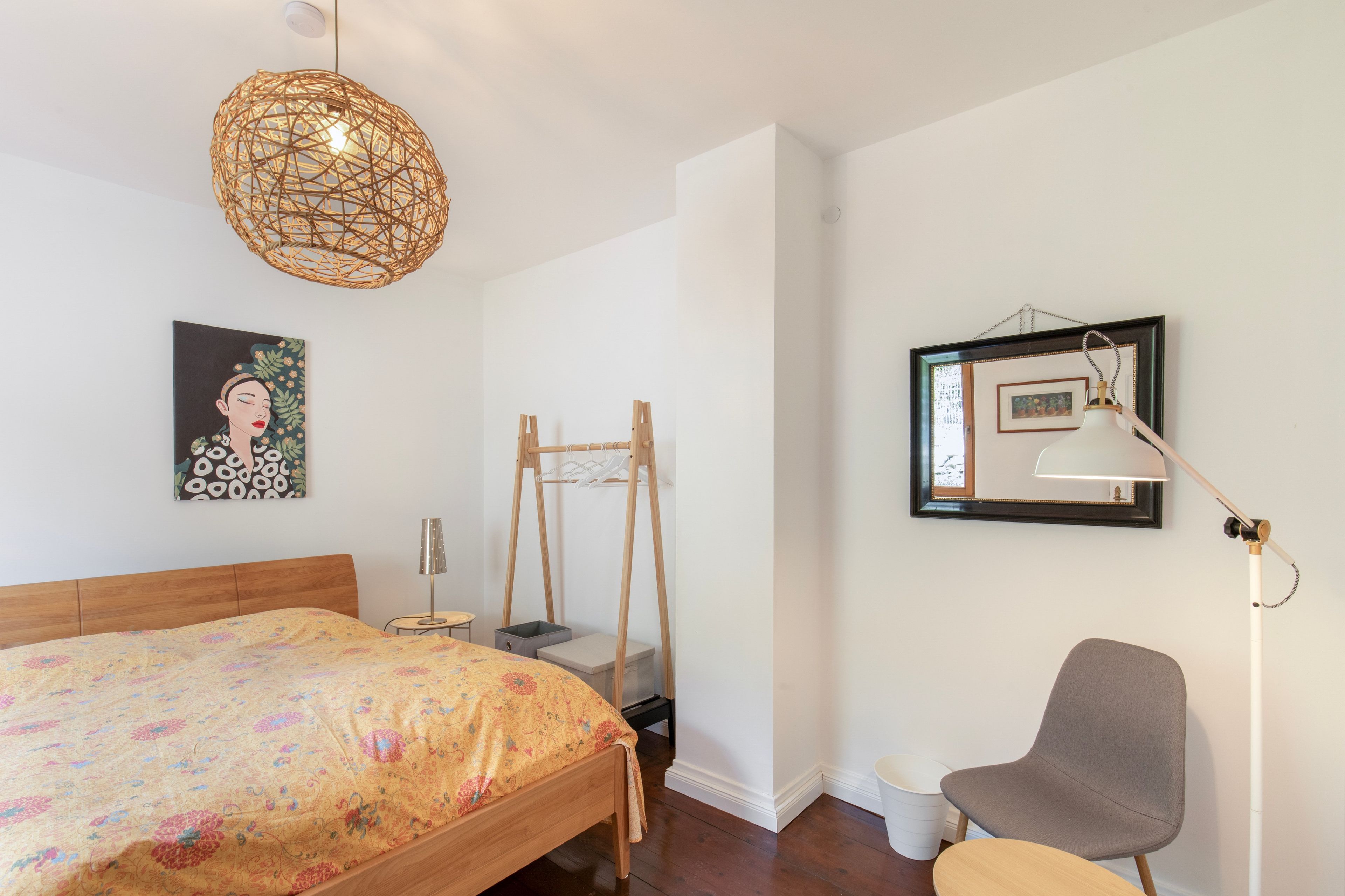 Une chambre à coucher comprenant un lit, un luminaire suspendu, une chaise, un bureau et une lampe fixée au mur.