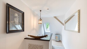 A hallway with a wooden boat sculpture, a framed picture, a hanging light fixture, and a mirror on the wall. - Holiday Home 'Hiwwelhaus' with Private Terrace, Private Garden and Wi-Fi (Oberdiebach)