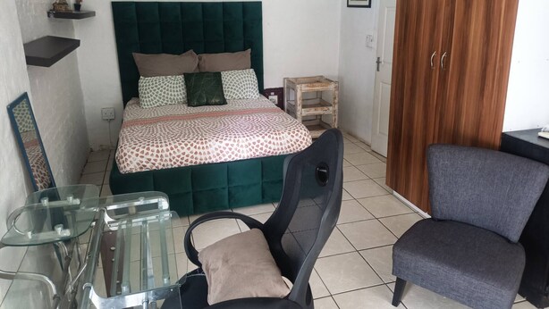 Un dormitorio con cama, escritorio, silla y armario.
