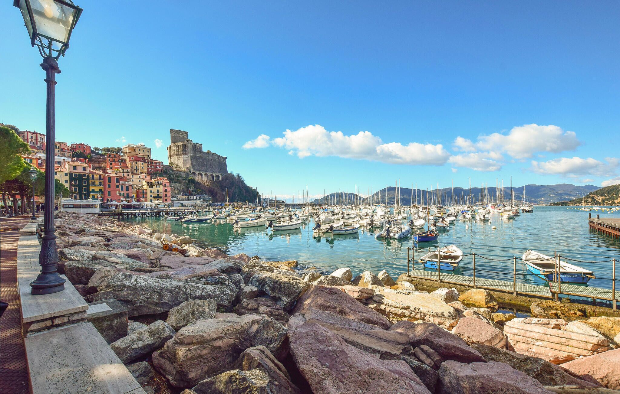 A coastal town with a historic fort, colorful buildings, and a marina with numerous boats.