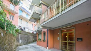 Eine enge Straße mit einem Gebäude, das einen verschlossenen Eingang und einen Balkon mit Metallgitteraufzug besitzt.