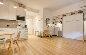 A modern kitchen with white cabinets, a dining area with a wooden table and chairs, and a whiteboard with a motivational quote. - Gorgeous apartment in Rapallo with WiFi (Rapallo)
