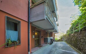 Eine schmale Gasse mit einem Gebäude links, einem verschlossenen Eingang und einem Motorrad davor.