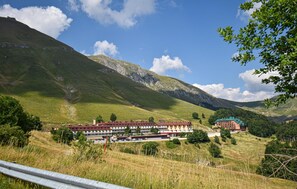 A hotel with multiple buildings, situated in a mountainous area with green hills and a clear sky. - Awesome apartment in Micigliano with WiFi (Micigliano)
