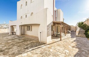 Ein Gebäude mit einer flachen Fassade, zahlreichen Fenstern und einer überdachten Außenbereich mit Tischen und Stühlen.