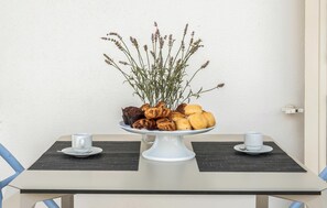 Et bord med et hvidt fad fyldt med kager og en vase med blomster.