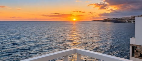 Atardecer sobre el mar con un balcón con vistas al agua.
