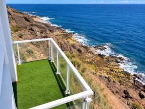 A balcony with a view of the ocean and rocky coastline. - 2BR La Furnia Home - Balcony & Natural Pool (Gáldar)