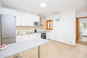 A modern kitchen with white cabinets, stainless steel appliances, and a herringbone floor pattern.