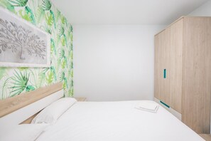 A bedroom with a bed, a wardrobe, and a wall with a leaf pattern. - 2BR La Furnia Home - Balcony & Natural Pool (Gáldar)