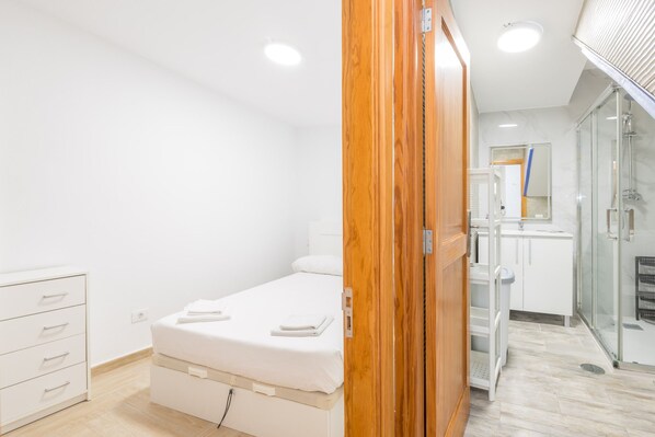 A bedroom with a bed, a wardrobe, and a bathroom with a shower.