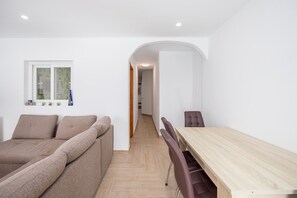Un salon moderne avec un canapé, une table à manger et des chaises, ainsi qu’un couloir menant à une autre pièce.