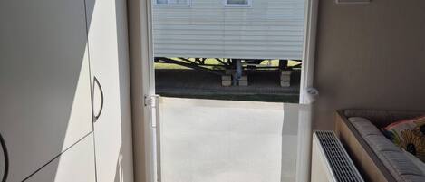 A room with a sliding door leading to a covered outdoor area, a radiator, and a window with blinds.