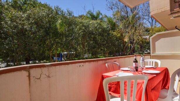 A balcony with a table set for two, white chairs, and a red tablecloth. - Amazing home in Piraino (Piraino)