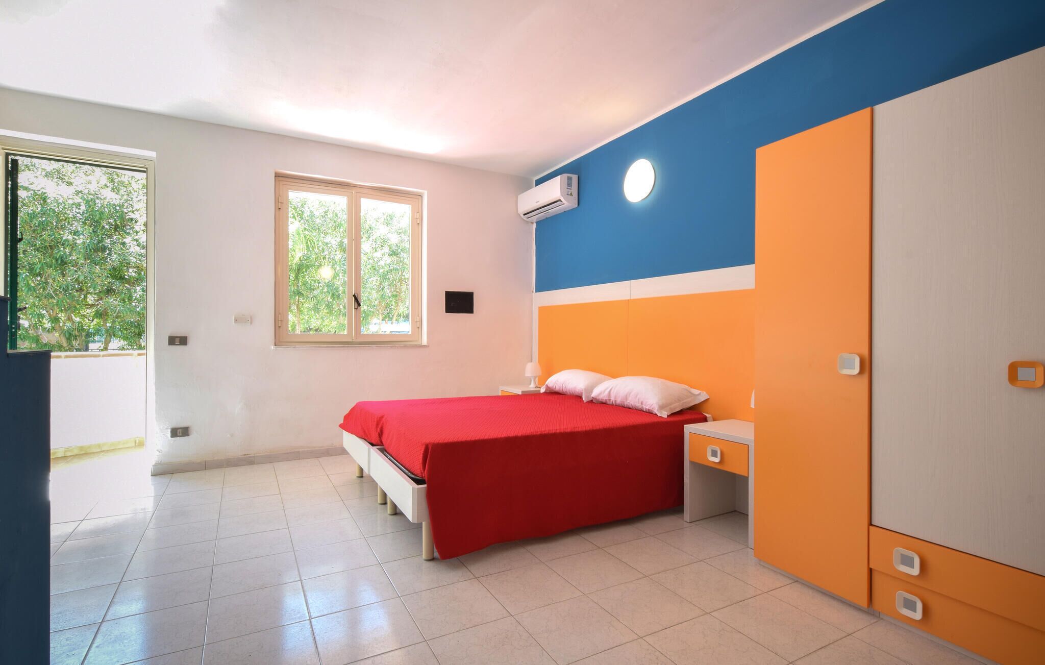 Een slaapkamer met een bed, een kledingkast, een raam en een airconditioning.