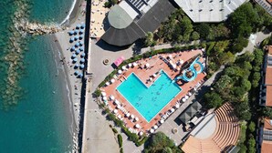 An aerial view of a resort with a central swimming pool, sun loungers, and a beach area. - Amazing home in Piraino (Piraino)