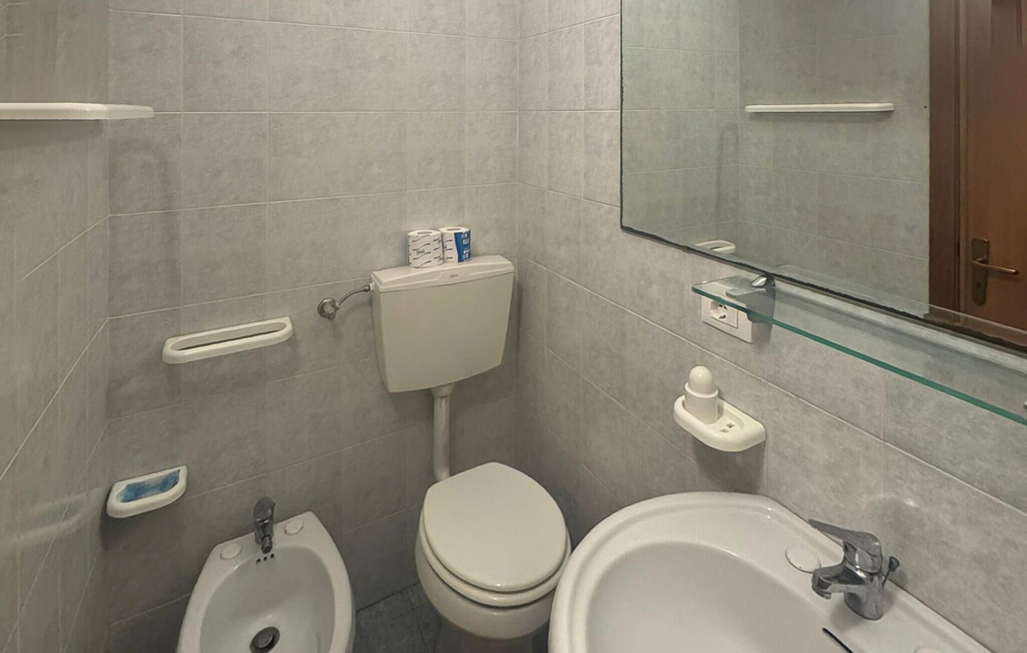 A bathroom with a toilet, bidet, and sink.