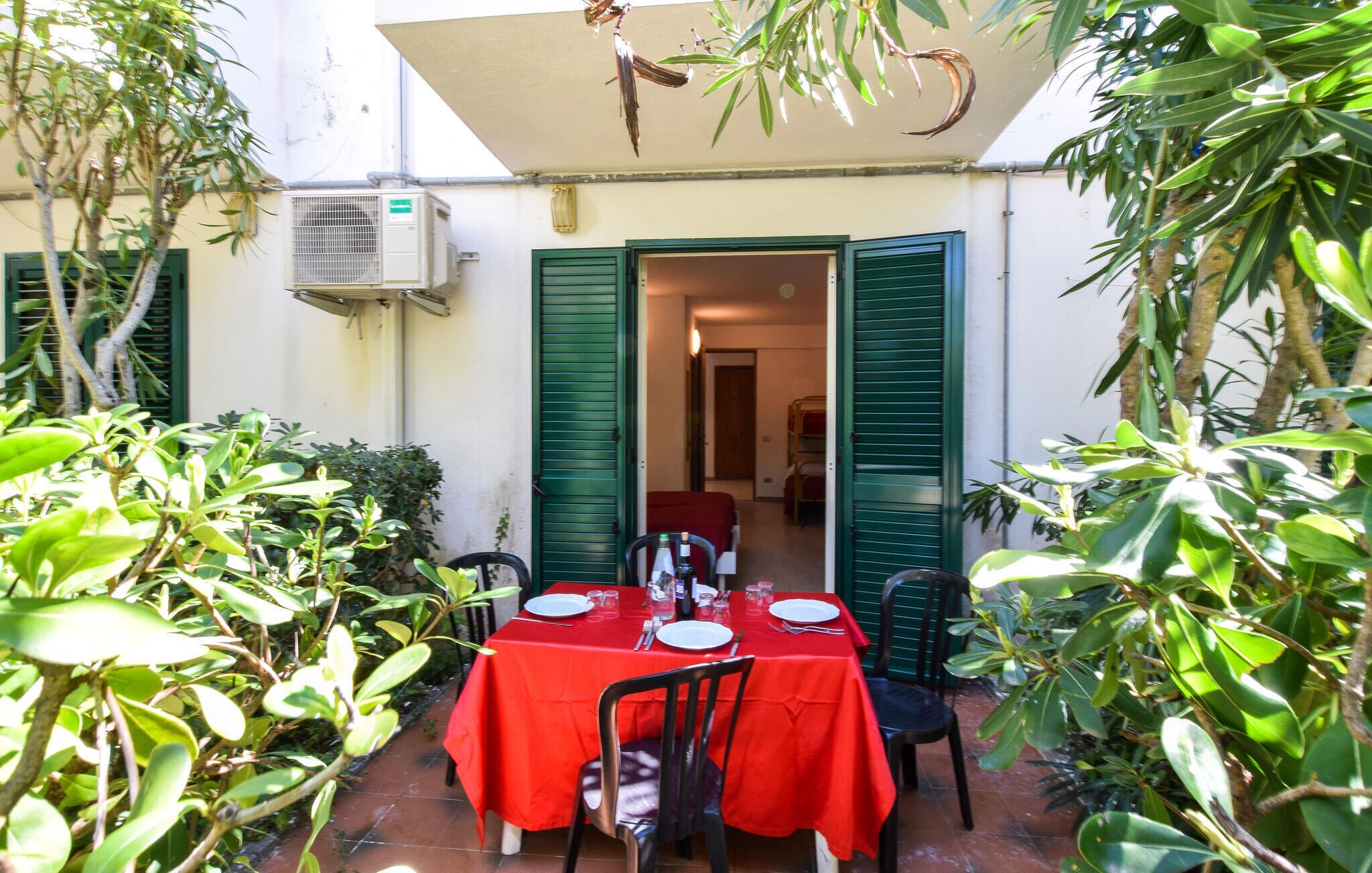 Een terras met tafels voor twee personen, omringd door groen.