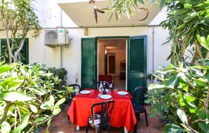Een terras met tafels voor twee personen, omringd door groen.