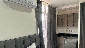 A hotel room with a bed, a small kitchenette, and a window with curtains. - Hotel The Silken Stay By Carlton Suites (Gurugram)