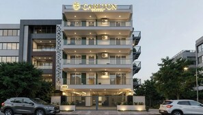 Un hotel de varios pisos con diseño moderno, con balcones en cada planta, y un letrero que indica el nombre 'Carlton Suites'.