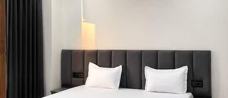 Un dormitorio moderno con una cama grande, una mesita de noche, una lámpara de pared y un ventilador de techo.