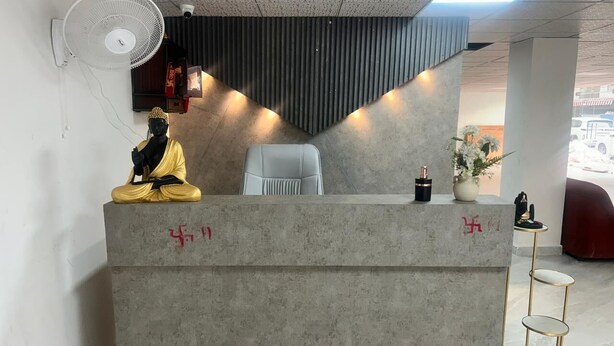 A reception desk with a statue, a fan, and a vase with flowers. - Hotel The Silken Stay By Carlton Suites (Gurugram)