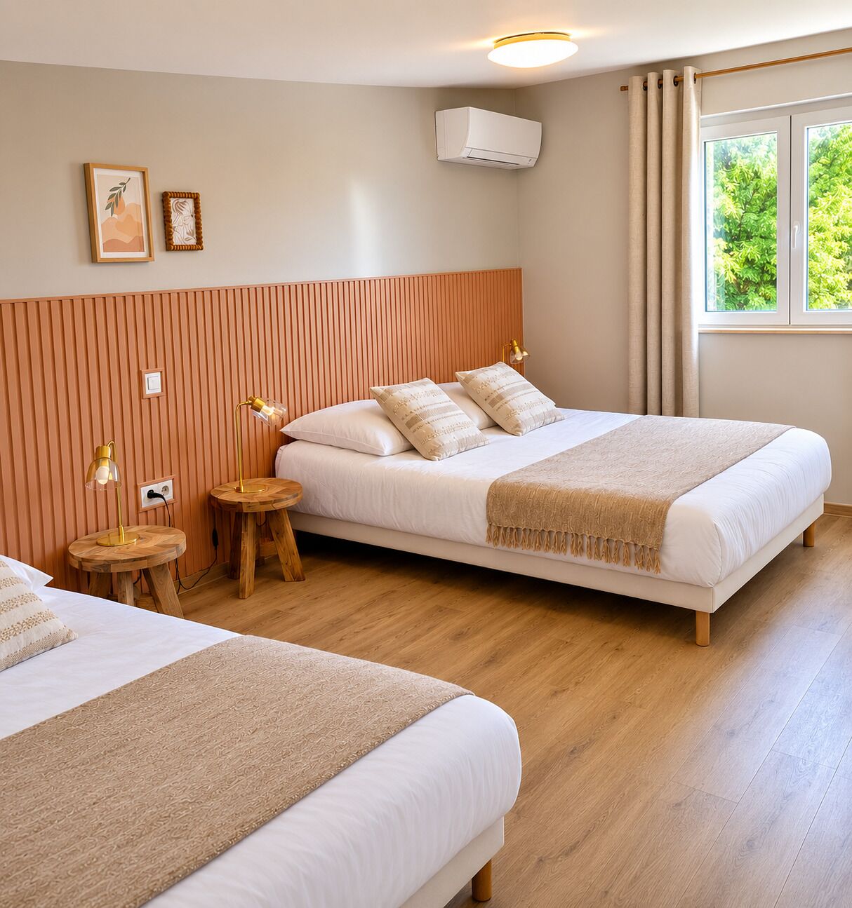 A hotel room with two beds, a wooden headboard, a window with curtains, and a wall-mounted air conditioner.