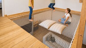 Una habitación con suelo de madera, techo bajo y una cama con estructura metálica.