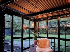 A room with large windows, a wooden ceiling, and a chair with a potted plant.