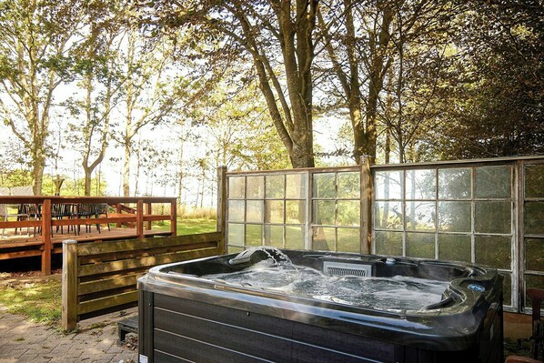 A hot tub in a wooded area with a wooden deck and benches. - Classic 1960s holiday home with Limfjord views (Fur)