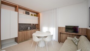 A modern living room with a sofa, a TV, and a dining area with chairs and a table. - Cozy apartment in Marina di Ragusa with house a panoramic view (Marina di Ragusa)
