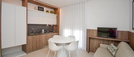 Een moderne woonkamer met een bank, een televisie en een eethoek met stoelen en een tafel.