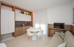 A modern living room with a sofa, a TV, and a dining area with chairs and a table. - Cozy apartment in Marina di Ragusa with house a panoramic view (Marina di Ragusa)