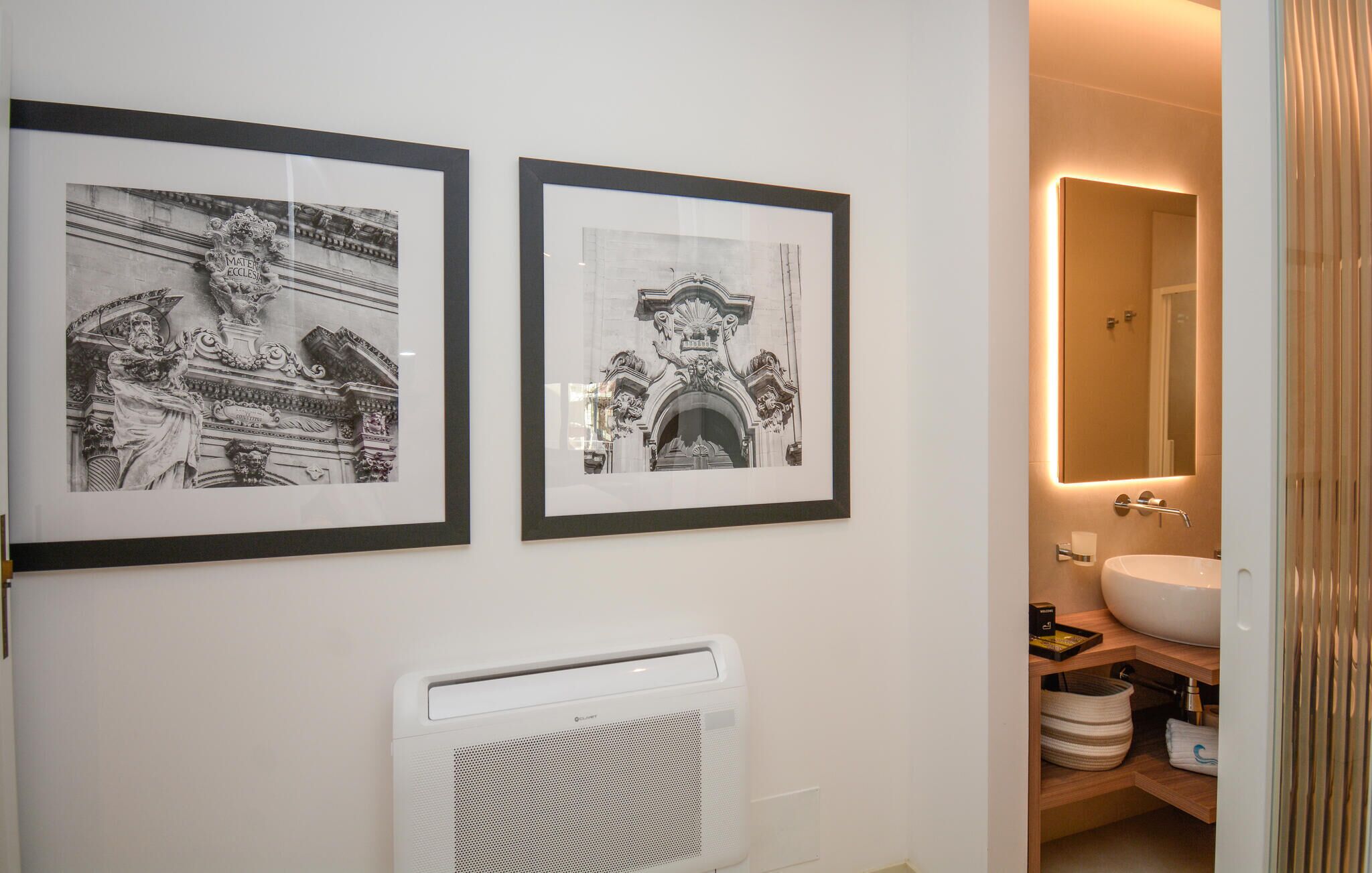 A bathroom with a white sink, a mirror, and two framed black and white photographs on the wall.