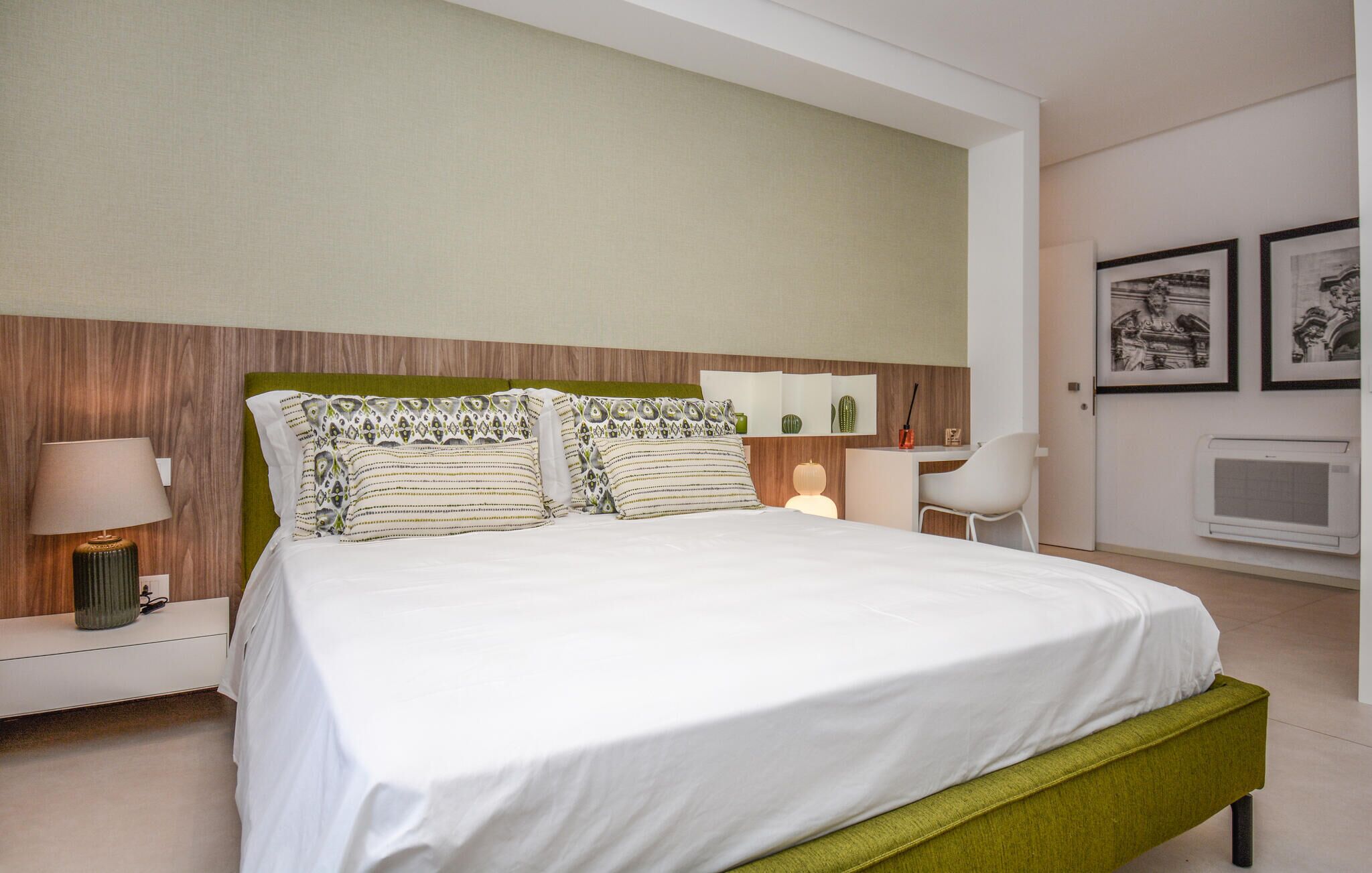 Une chambre d’hôtel comprenant un lit, une table de chevet, une lampe et un bureau avec une chaise.