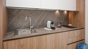 A modern kitchen with a built-in sink, a coffee maker, and a kettle on the countertop. - Cozy apartment in Marina di Ragusa with house a panoramic view (Marina di Ragusa)