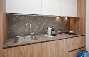 A modern kitchen with a built-in sink, a coffee maker, and a kettle on the countertop. - Cozy apartment in Marina di Ragusa with house a panoramic view (Marina di Ragusa)