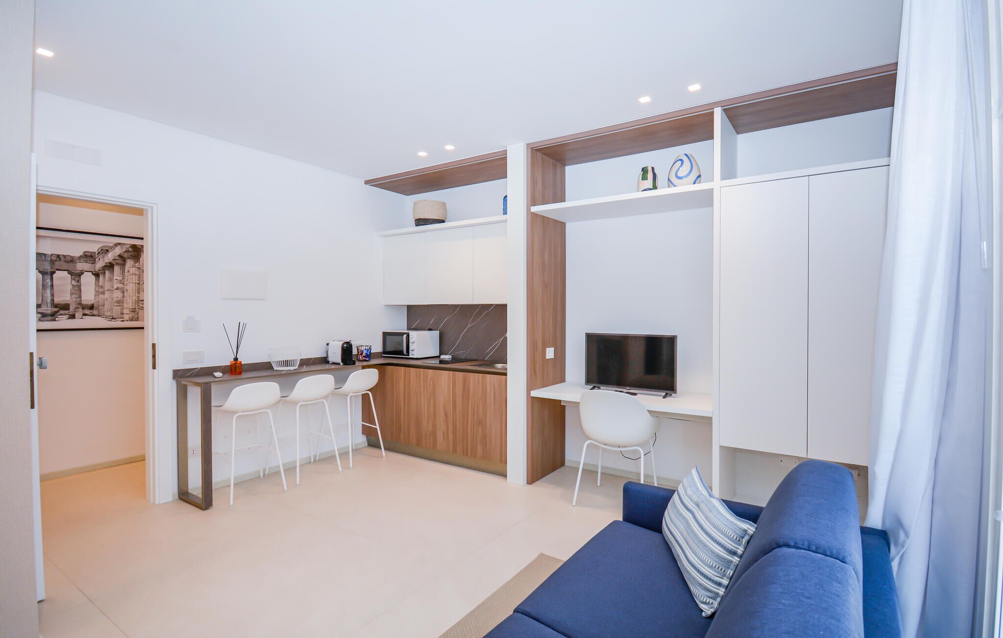 Un appartement moderne comprenant un coin cuisine, un espace repas, un salon avec un canapé et un téléviseur.