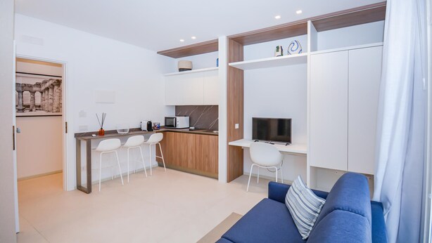 Eine moderne Wohnung mit Küchenzeile, Essbereich, Wohnzimmer mit Sofa und Fernseher.