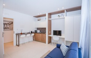 Un apartamento moderno con kitchenette, comedor, sala de estar con sofá y televisor.