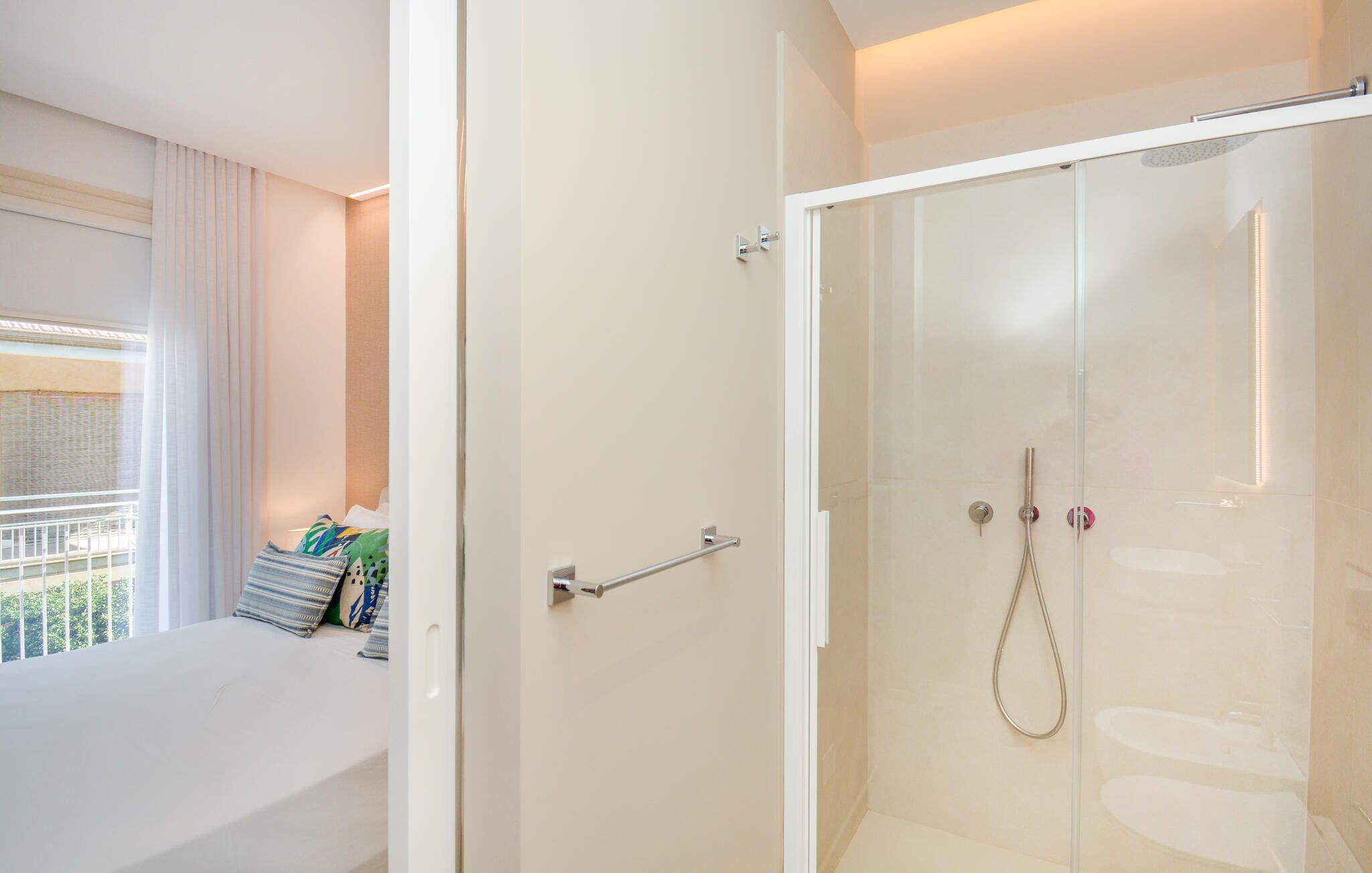 Un baño moderno con ducha envuelta en vidrio, una bañera blanca y vistas al exterior.