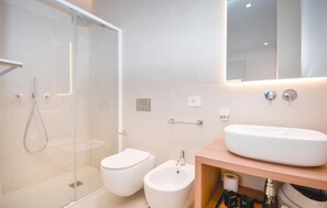 A modern bathroom with a glass shower enclosure, a toilet, a bidet, and a sink with a wooden vanity. - Nice apartment in Marina di Ragusa with WiFi (Marina di Ragusa)
