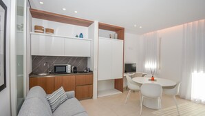 A modern kitchen with a microwave, kettle, and cabinets. There is a dining area with a table and chairs, and a living area with a sofa. - Stunning apartment in Marina di Ragusa with WiFi (Marina di Ragusa)