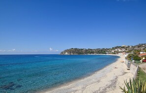 A coastal beach with clear blue waters, a sandy shore, and a hillside with buildings. - Stunning apartment in Marina di Ragusa with WiFi (Marina di Ragusa)