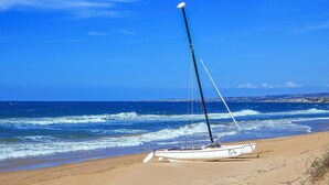 Ein Segelboot an einem sandigen Strand mit dem Ozean im Hintergrund.