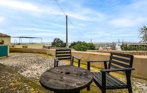 Ein Sitzbereich im Freien mit einem runden Tisch und zwei Stühlen, mit Blick auf eine Stadtlandschaft.