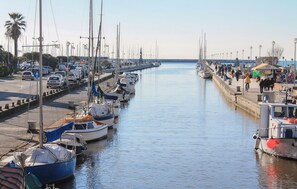 Ein Yachthafen mit vertäuten Booten entlang der Uferpromenade, ein Fußweg und ein klarer Himmel.